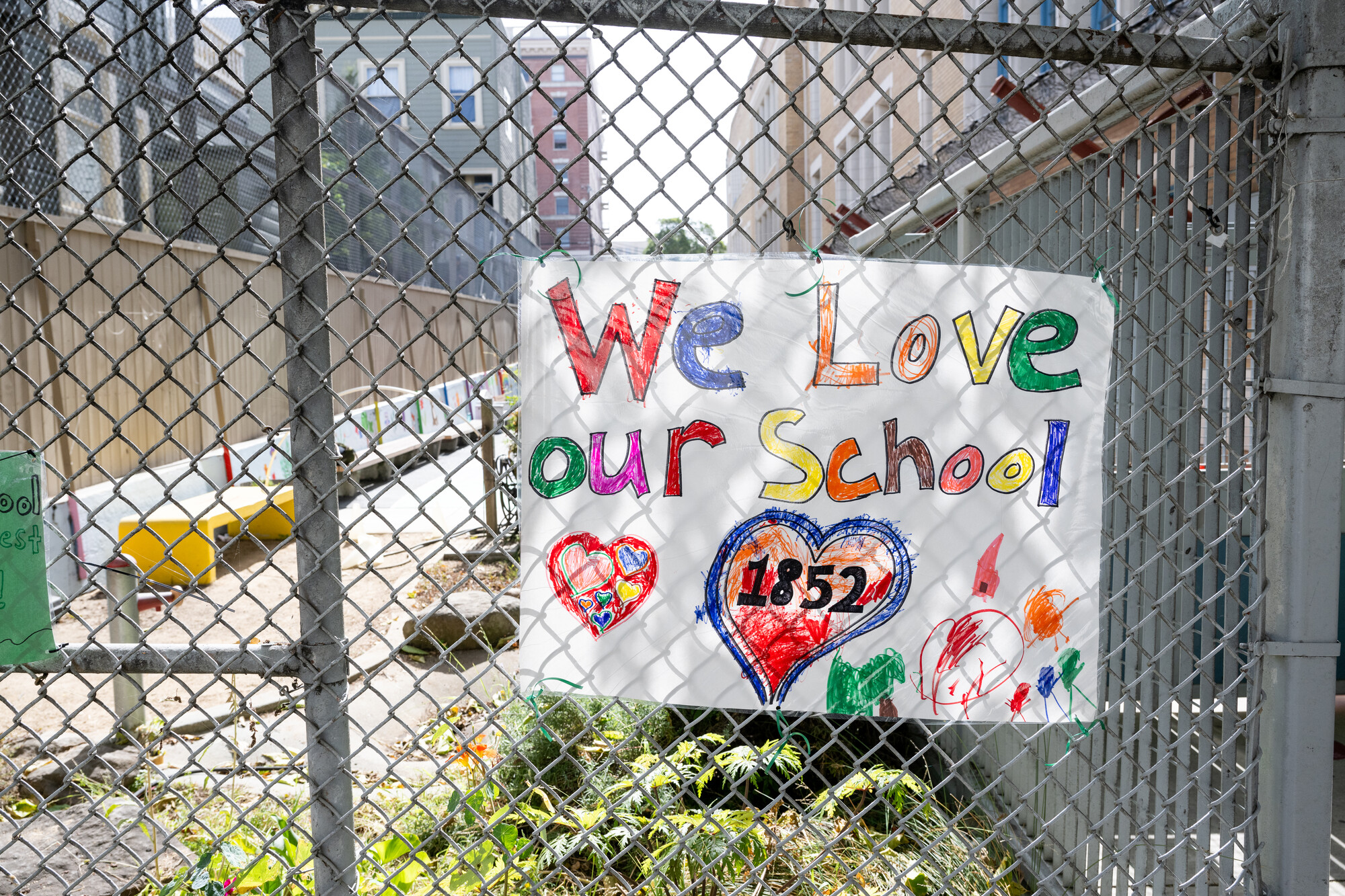 Signs cover the fence in front of Spring Valley Science Elementary school in San Francisco during a press conference on Oct. 10, 2024, to push for city intervention in SFUSD’s school closure plans.